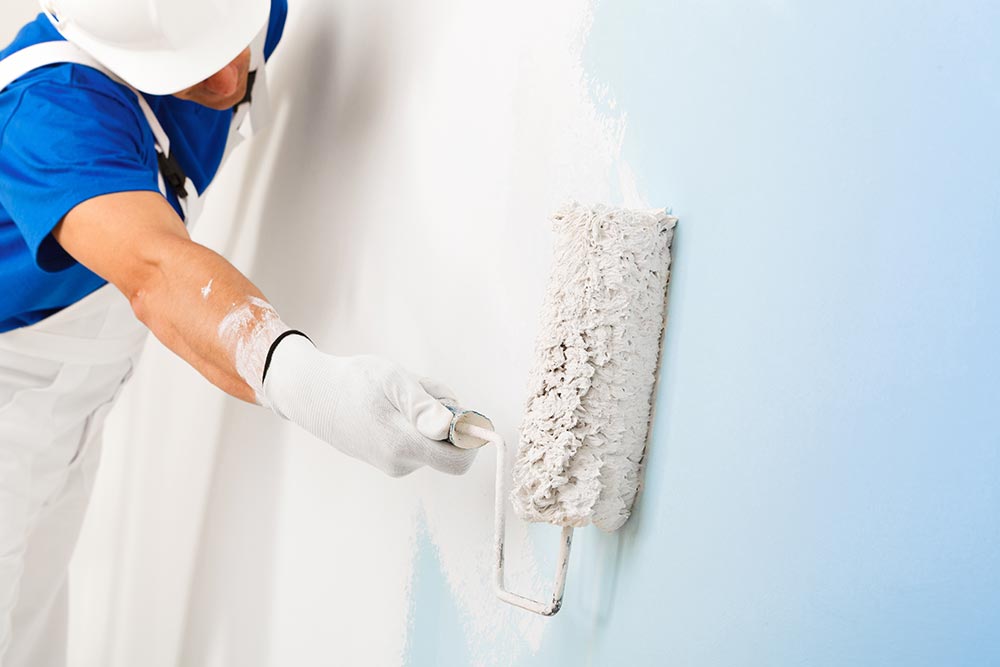 Arbeiter der Innenmalerei in Strobl streicht blaue Wand weiß