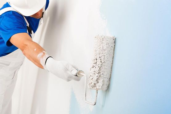 Arbeiter der Innenmalerei in Strobl streicht blaue Wand weiß